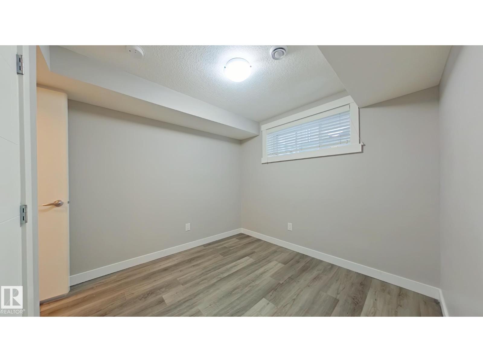 A room with wooden flooring and a window with blinds.