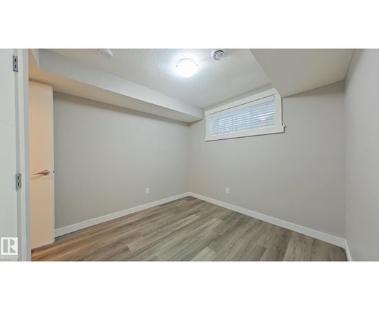 A room with wooden flooring and a window with blinds.