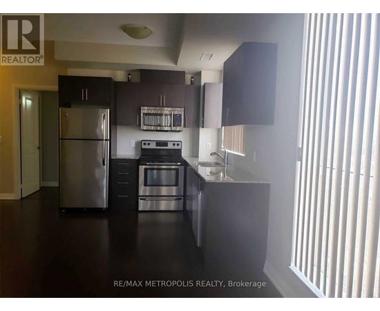 A kitchen with a refrigerator, microwave, oven, and sink.