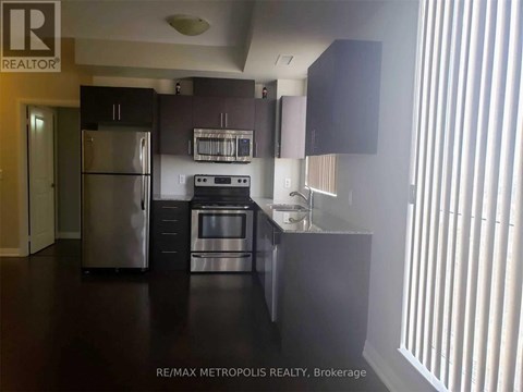 A kitchen with a refrigerator, microwave, oven, and sink.