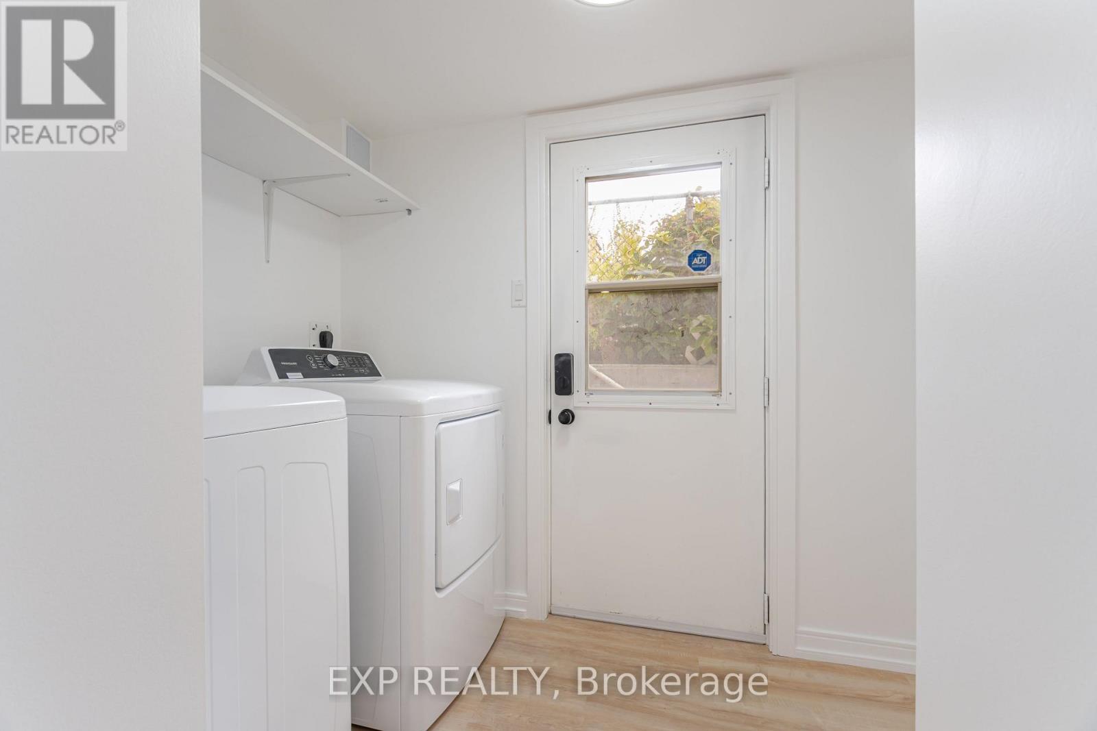 A white door with a black handle is in a room with a washing machine and a dryer.