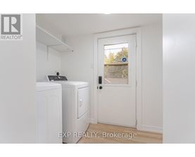 A white door with a black handle is in a room with a washing machine and a dryer.