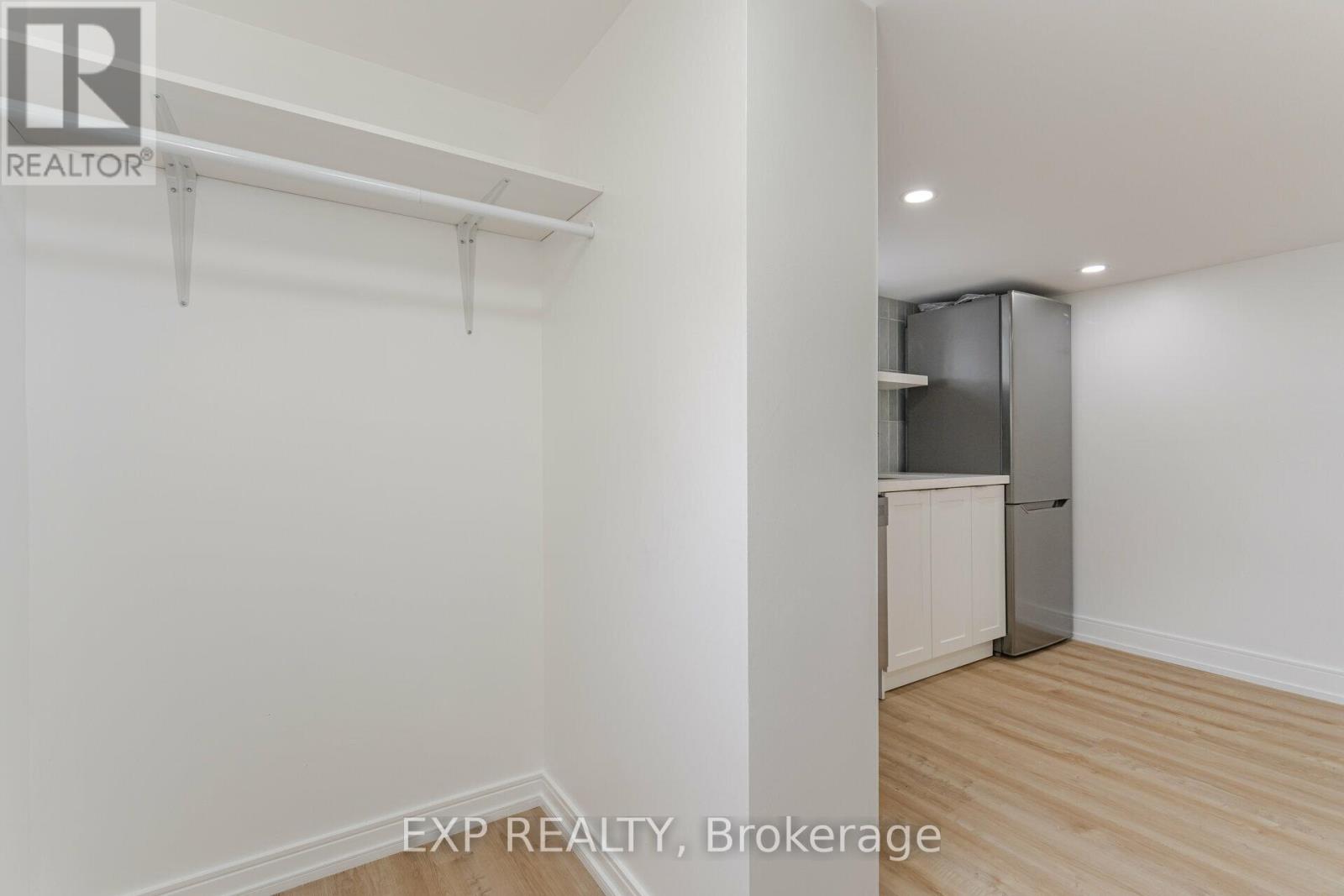 A white wall with a kitchen in the corner.