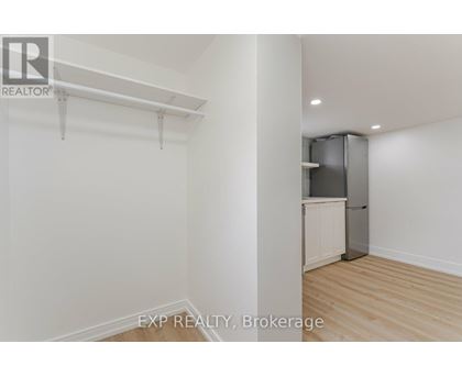 A white wall with a kitchen in the corner.