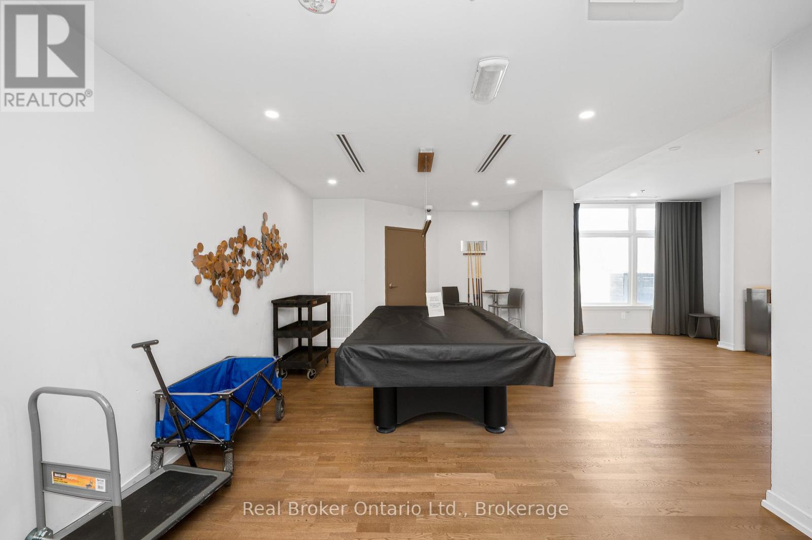 A bedroom with a black bed and a wooden floor.