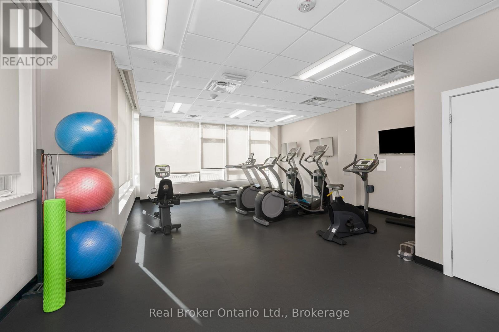 A gym with exercise equipment and a Real Broker logo.