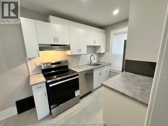 A kitchen with white cabinets and a black stove top oven.
