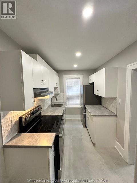 A kitchen with white cabinets and a black stove top oven.