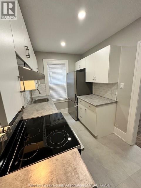 A kitchen with a black stove top oven and white cabinets.
