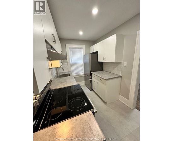 A kitchen with a black stove top oven and white cabinets.