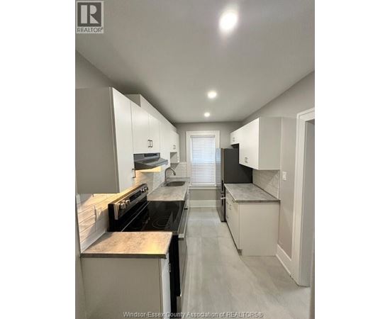 A kitchen with white cabinets and a black stove top oven.