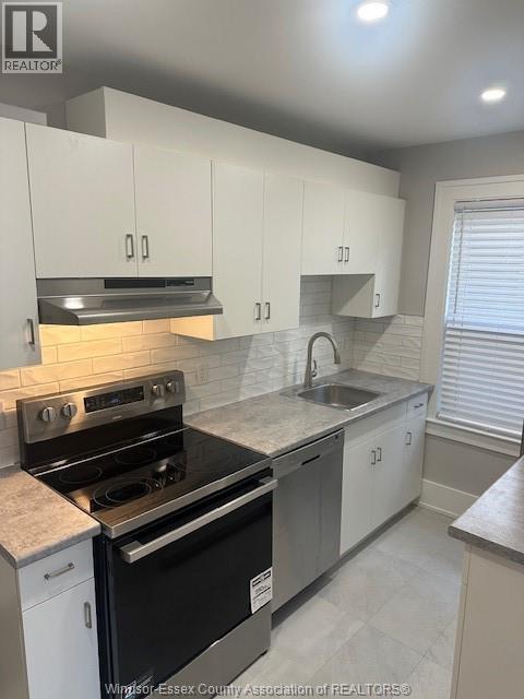 A kitchen with white cabinets and a black stove top oven.