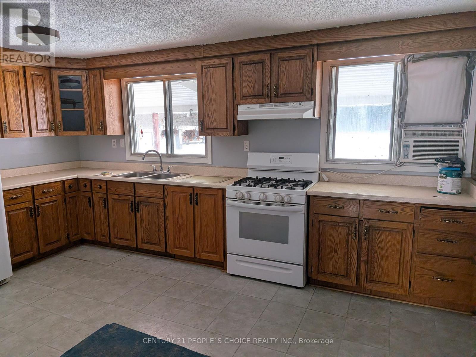 A kitchen with wooden cabinets and a white stove top oven.