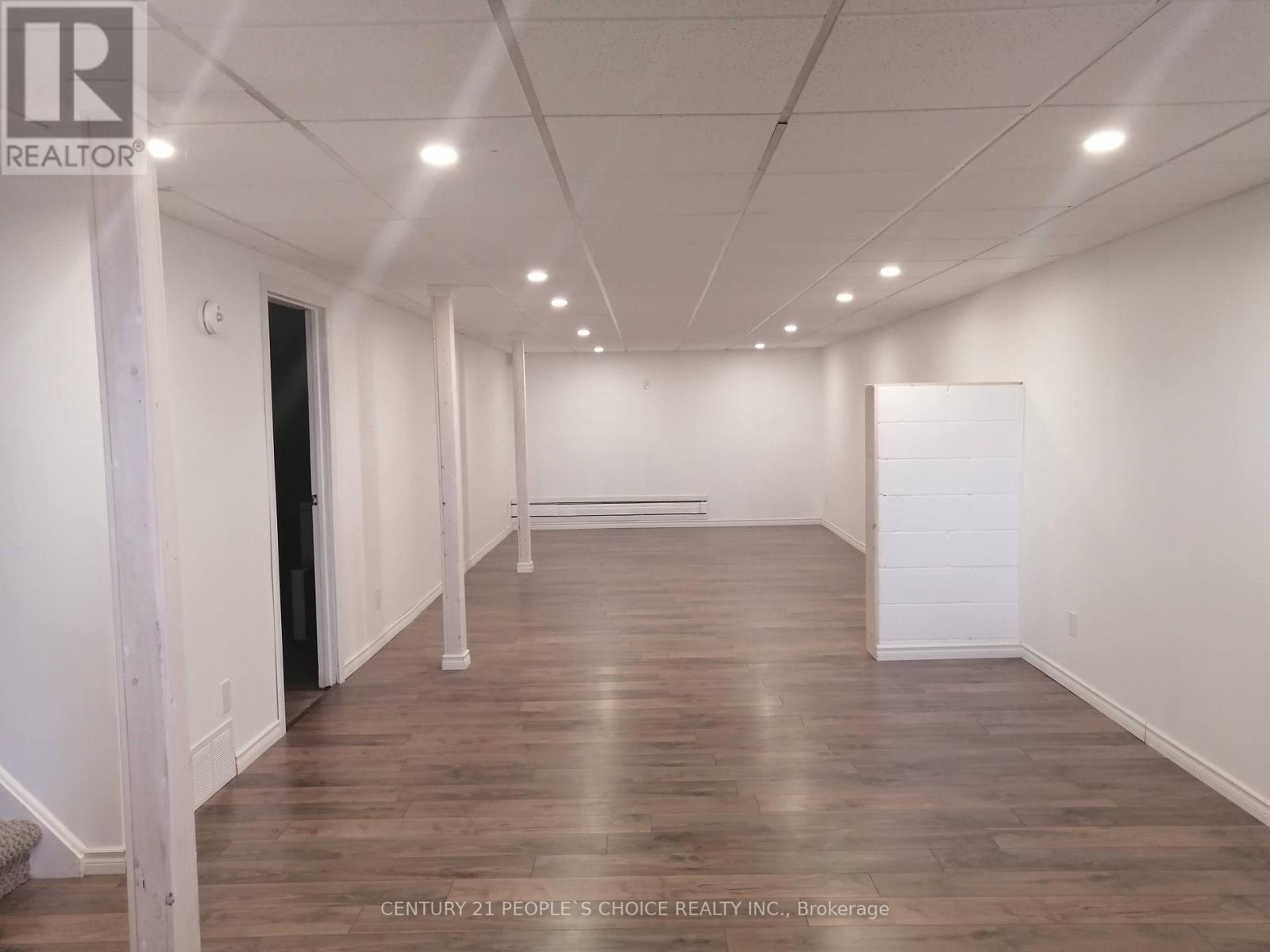 A spacious room with wooden flooring and white walls, likely a property for sale.