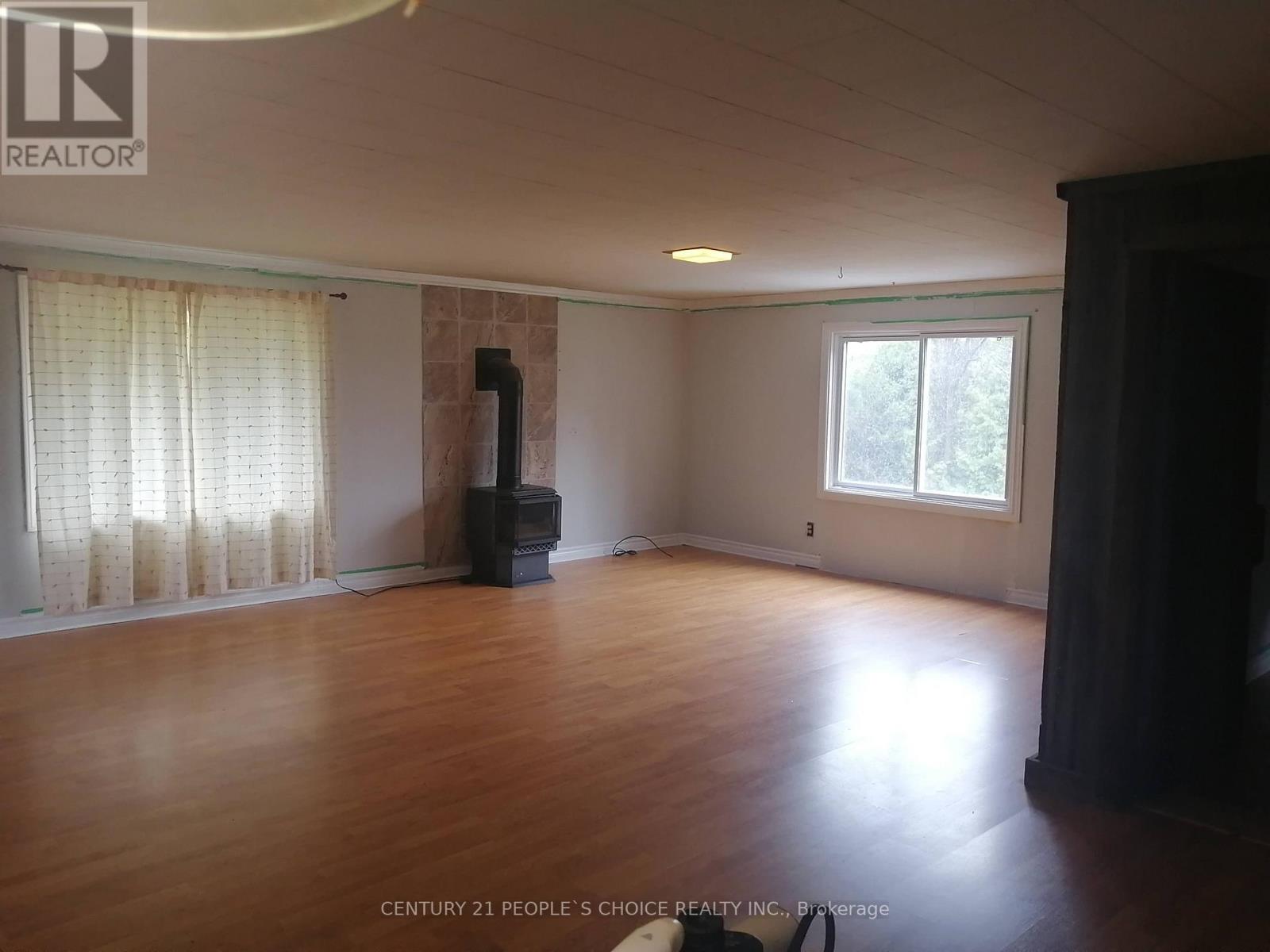 A room with wooden floors and a window with white curtains.