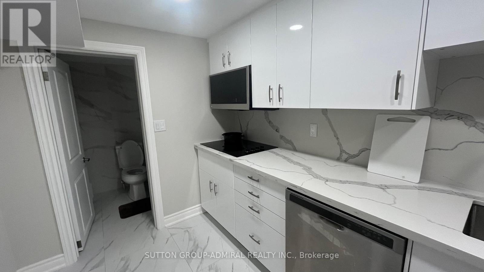 A kitchen with white cabinets and a marble countertop.