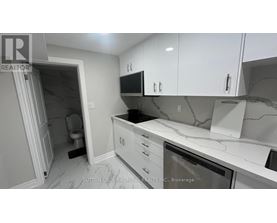 A kitchen with white cabinets and a marble countertop.
