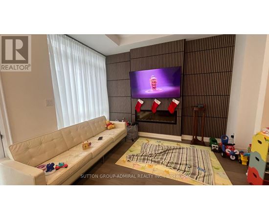 A living room with a white sofa, a fireplace, and a television displaying a cartoon character.
