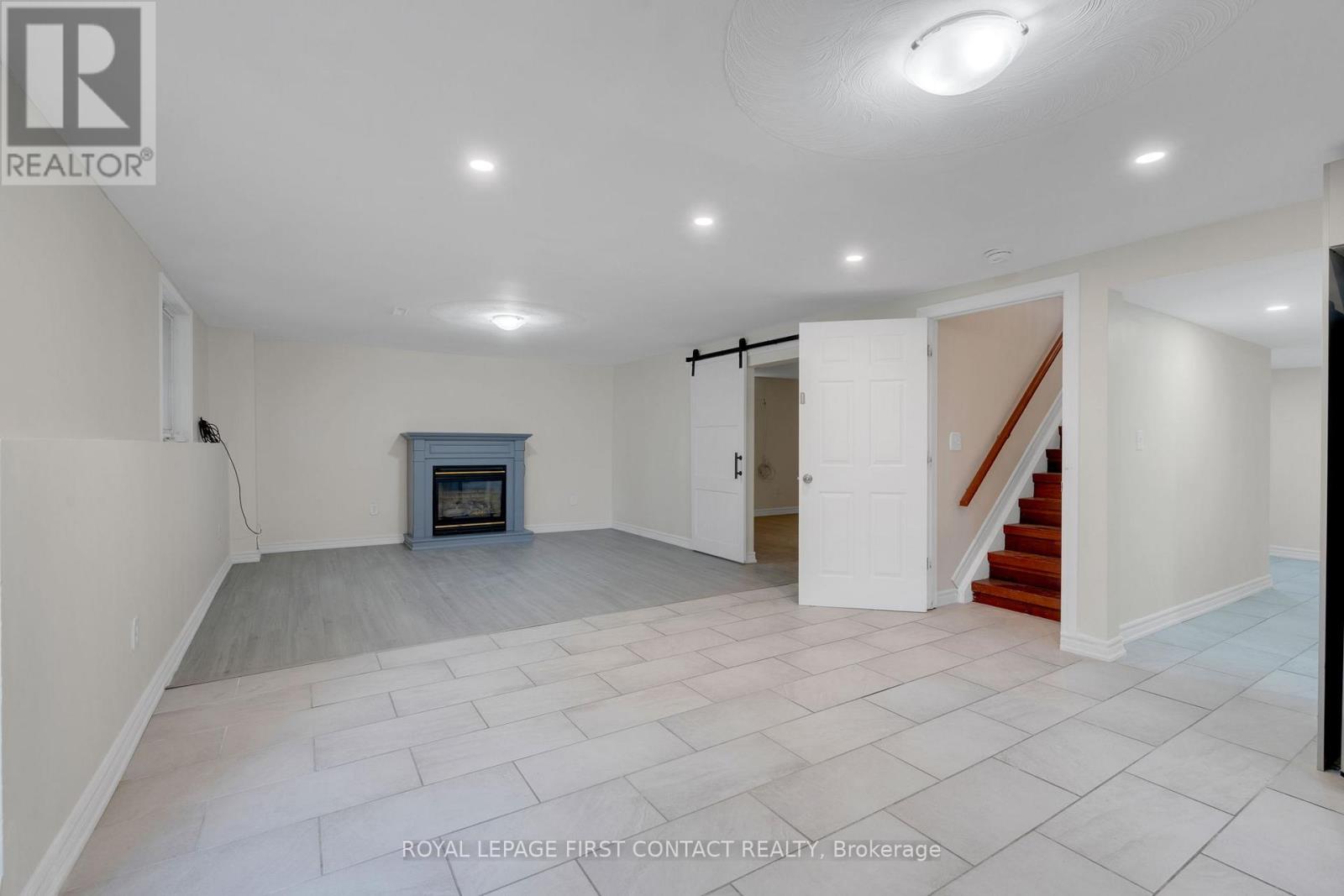 A spacious room with a fireplace and a staircase.