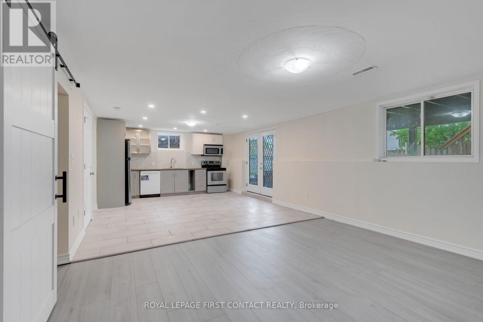 A spacious, empty room with a kitchenette in the background.