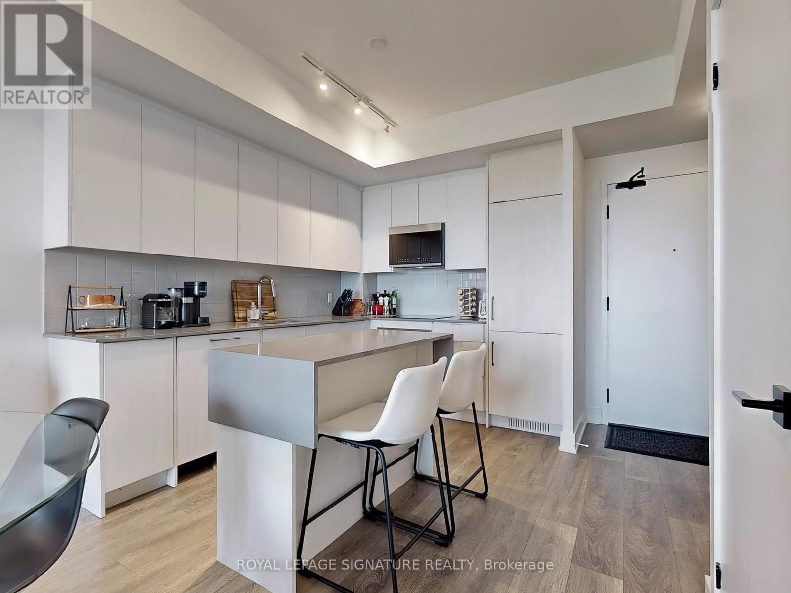 A kitchen with white cabinets and a black chair.