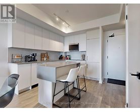 A kitchen with white cabinets and a black chair.
