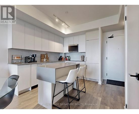 A kitchen with white cabinets and a black chair.