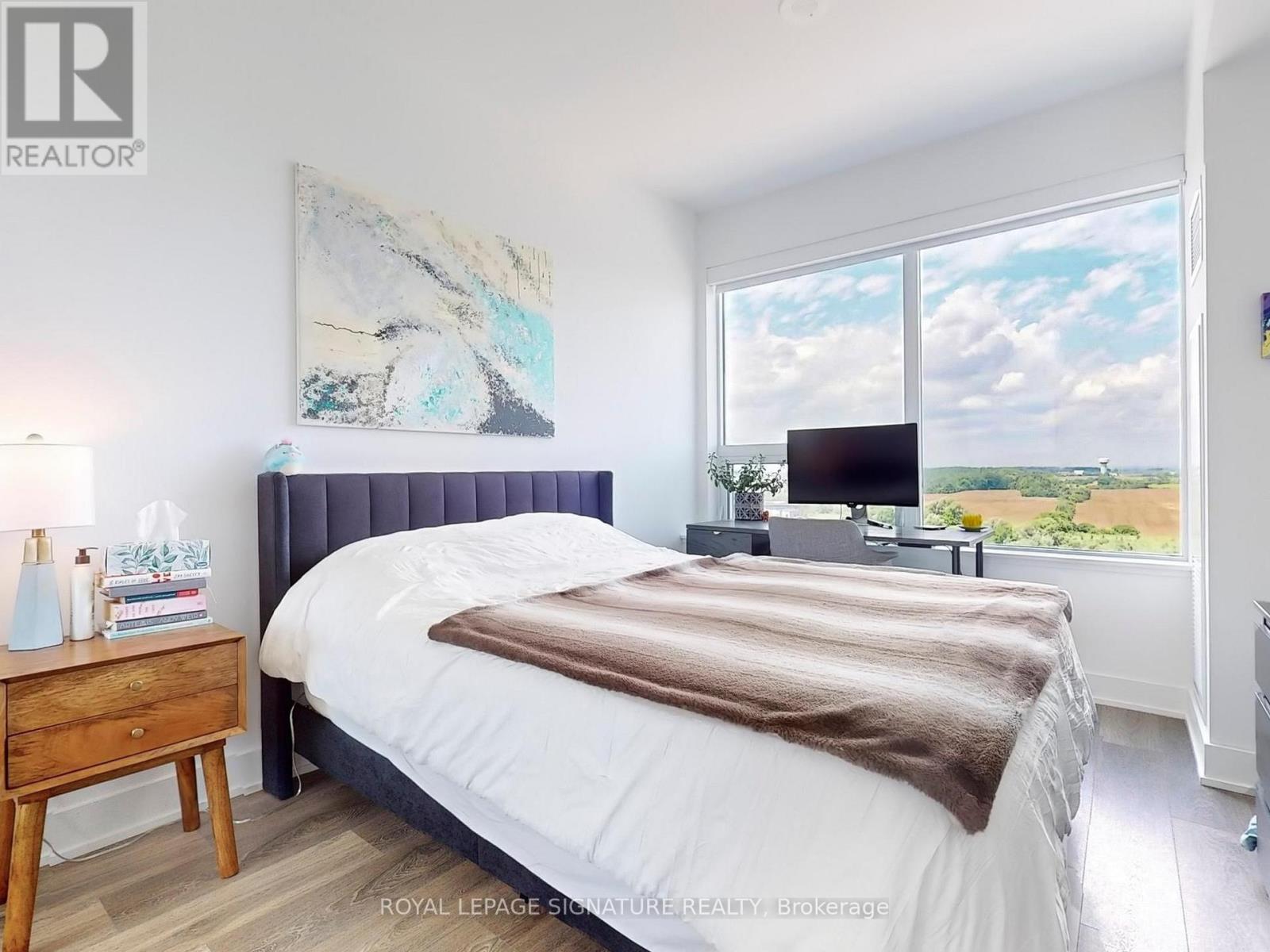 A bedroom with a large bed and a painting on the wall.
