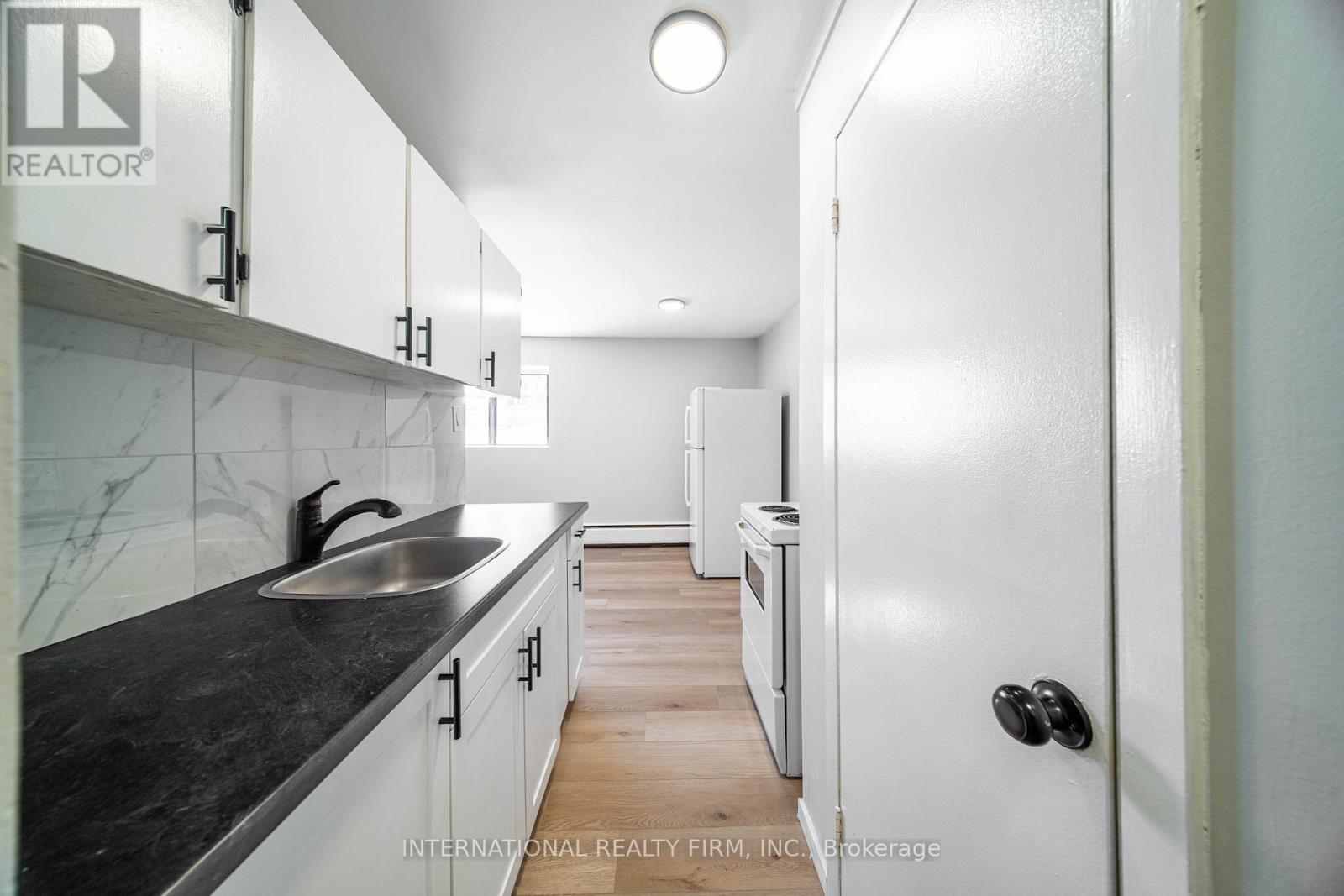 A modern kitchen with white cabinets and a black countertop.