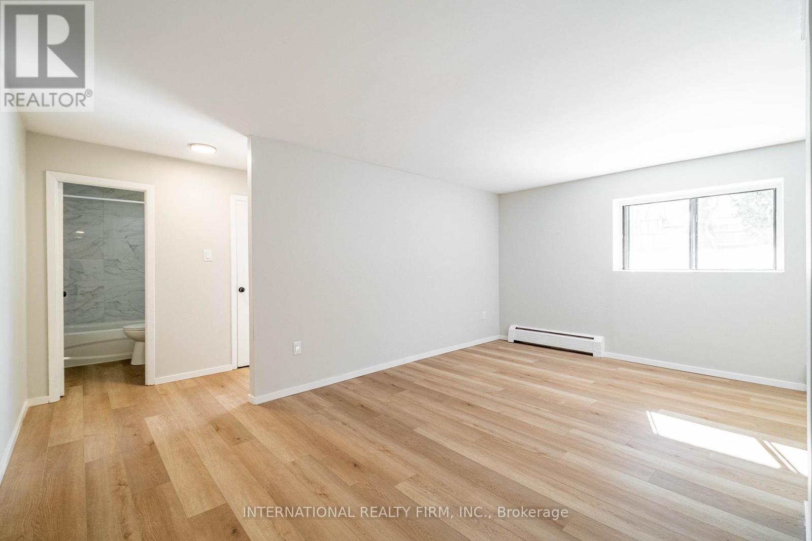 A room with wooden flooring and white walls.