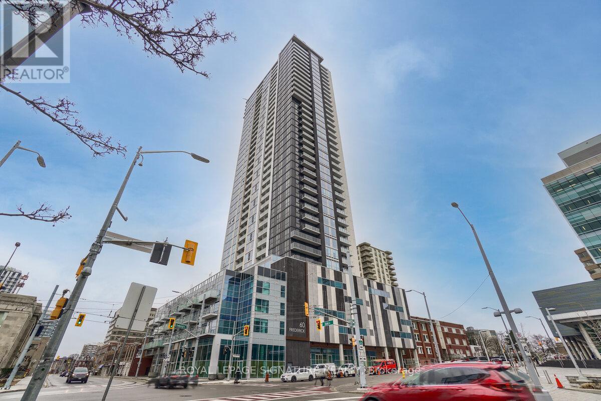 A tall building with many windows is in the middle of a city street.