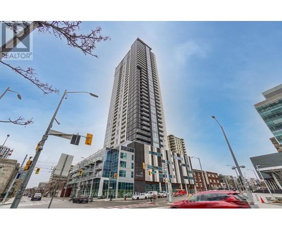 A tall building with many windows is in the middle of a city street.