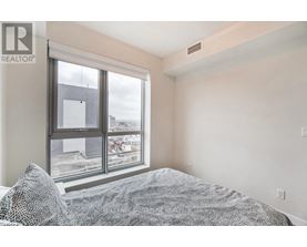 A bedroom with a large bed and a window overlooking a cityscape.