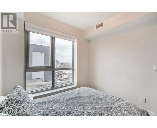 A bedroom with a large bed and a window overlooking a cityscape.