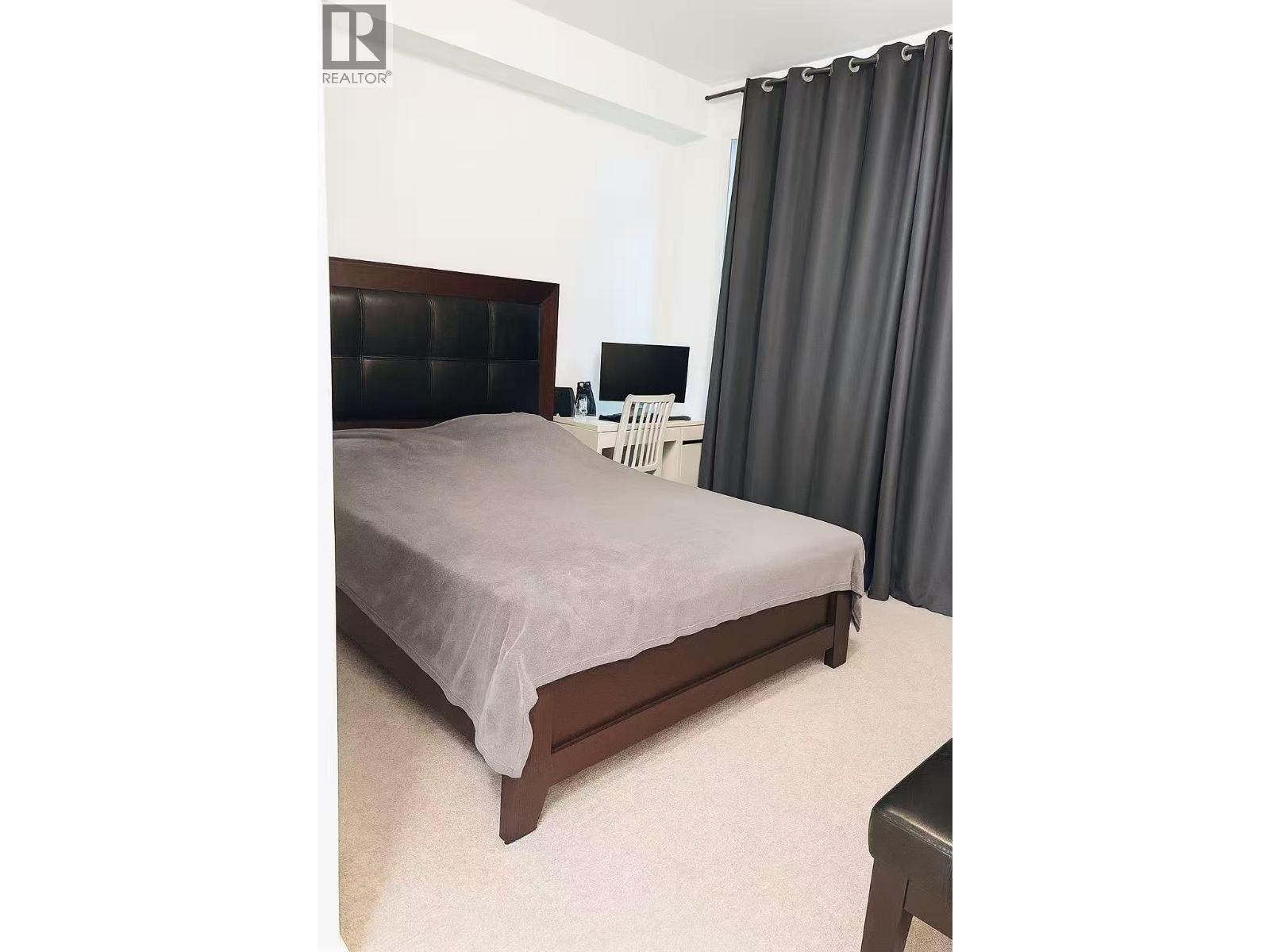 A bedroom with a bed, nightstand, and chair.