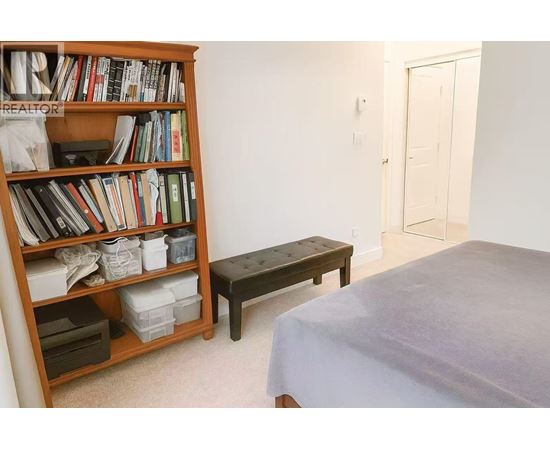 A bedroom with a bed, a bookshelf, and a bench.