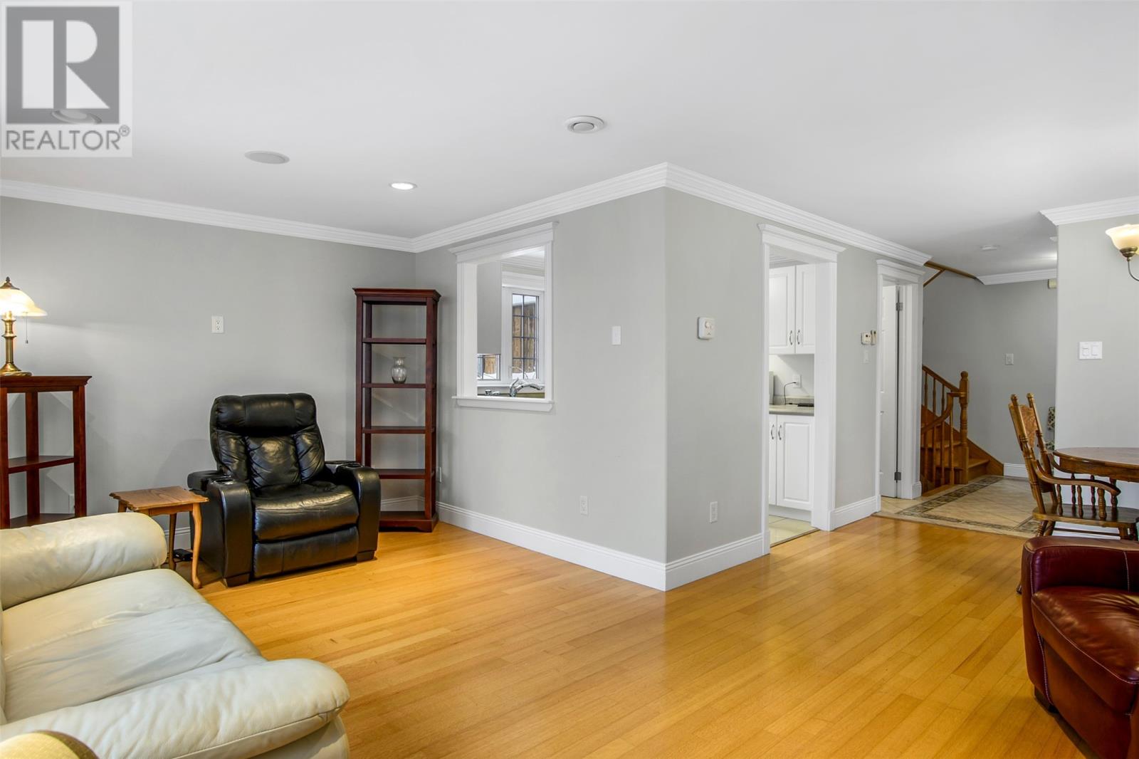 A living room with a black leather chair and a wooden floor.