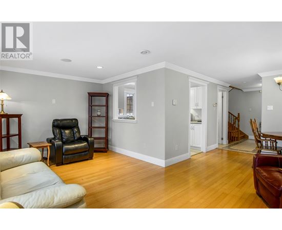 A living room with a black leather chair and a wooden floor.