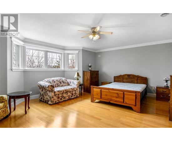 A bedroom with a bed, dresser, and chair.