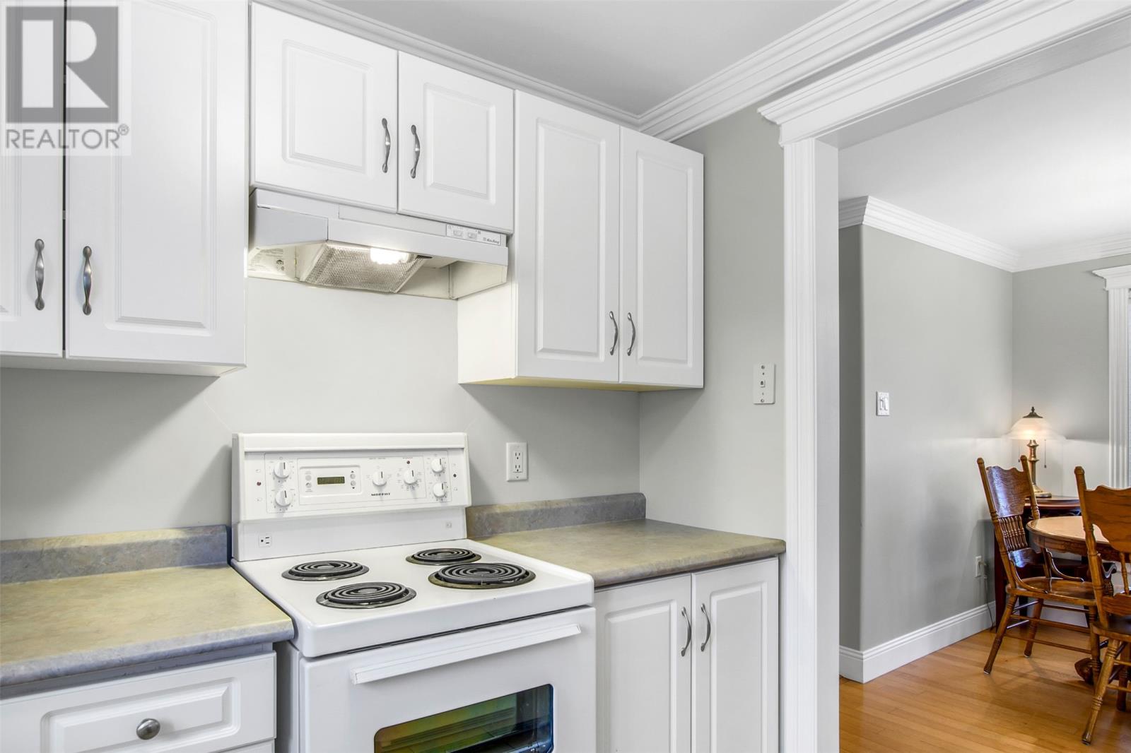 A white stove and oven in a kitchen with white cabinets.