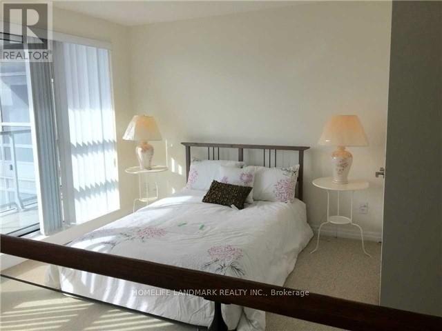 A bedroom with a bed, two lamps, and a window with curtains.
