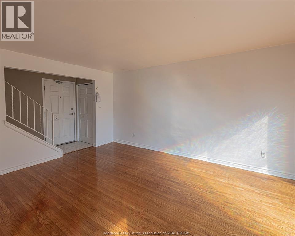 A room with wooden flooring and a staircase leading to another room.