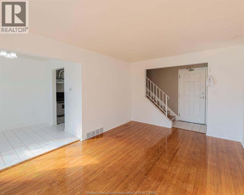A spacious room with wooden floors and a staircase leading to another room.