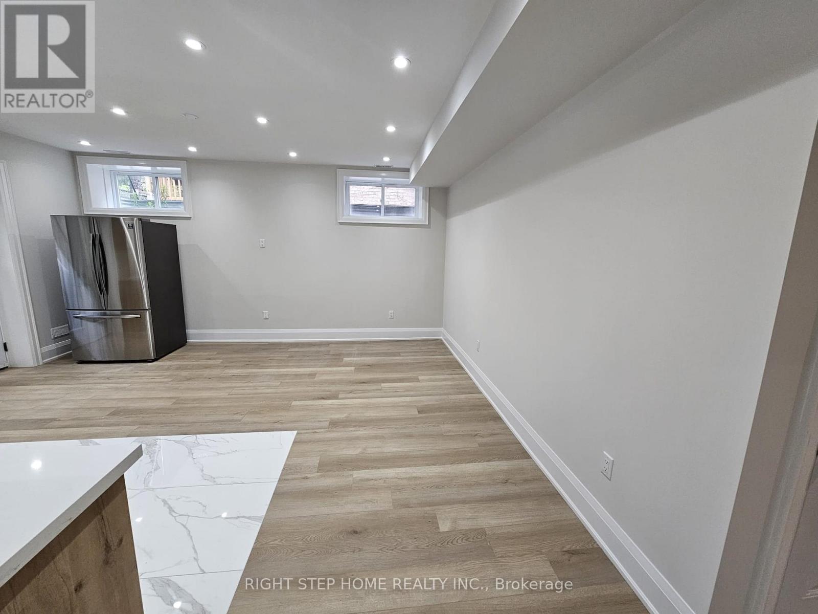 A spacious room with wooden flooring and white walls.