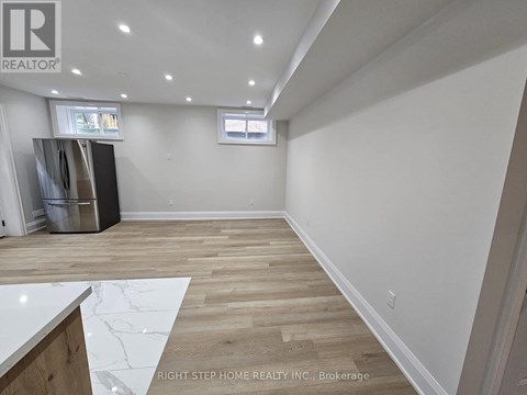 A spacious room with wooden flooring and white walls.
