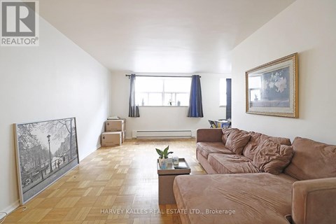 A living room with a brown couch and a painting on the wall.