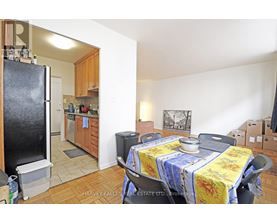 A kitchen with a refrigerator, table and chairs.