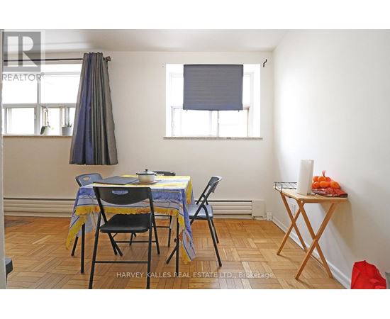 A dining room with a table set for two and a window with blinds.