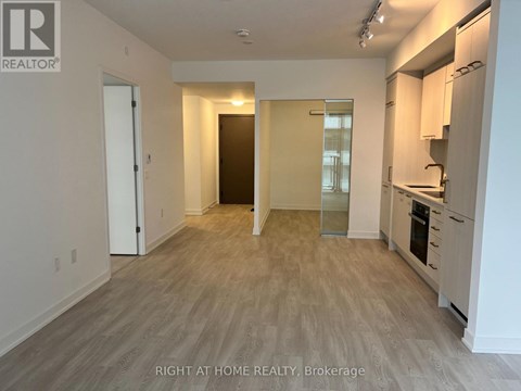 A spacious kitchen with white cabinets and a wooden floor.