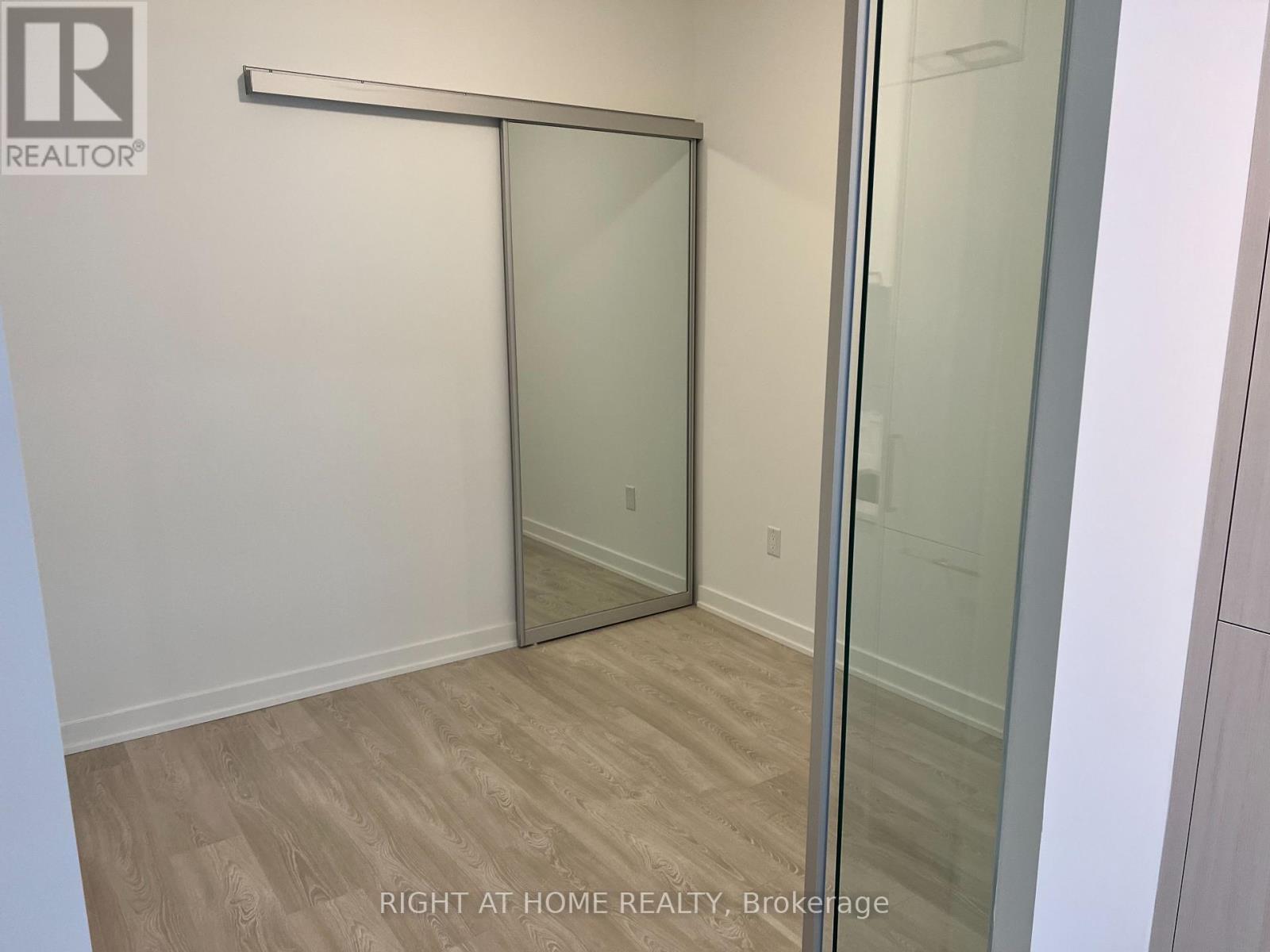 A room with a sliding glass door and wooden flooring.